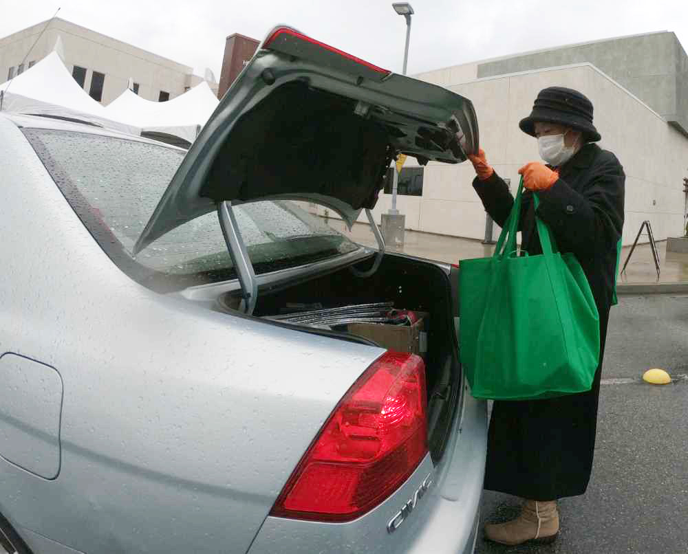 Dr. Audrey Yamagata-Noji loads groceries into trunk at drive-thru pantry
