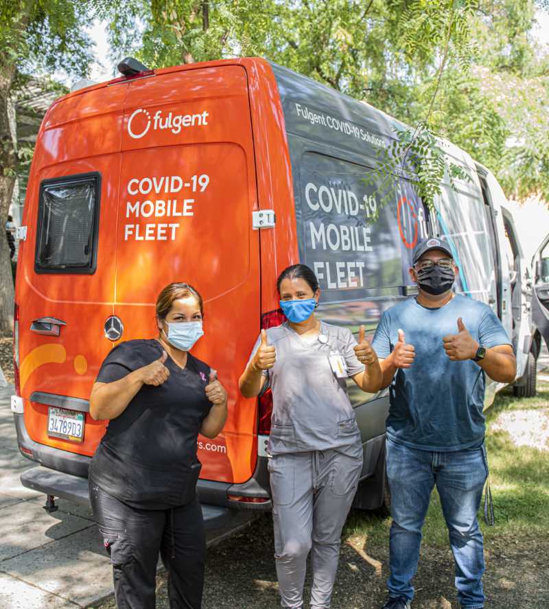 Nurse and workers give thumbs up in front of Fulgent mobile clinic van