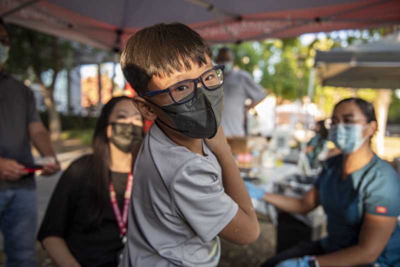 Child rolls up his sleeve to receive vaccine