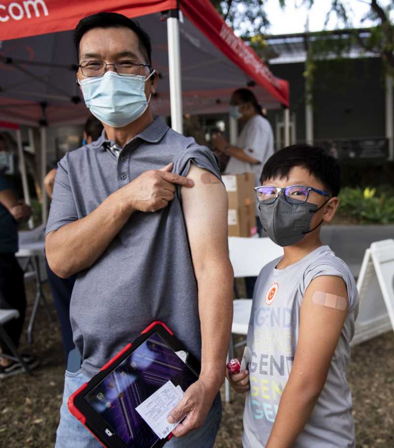 Man and his son show off their post-vaccine bandages
