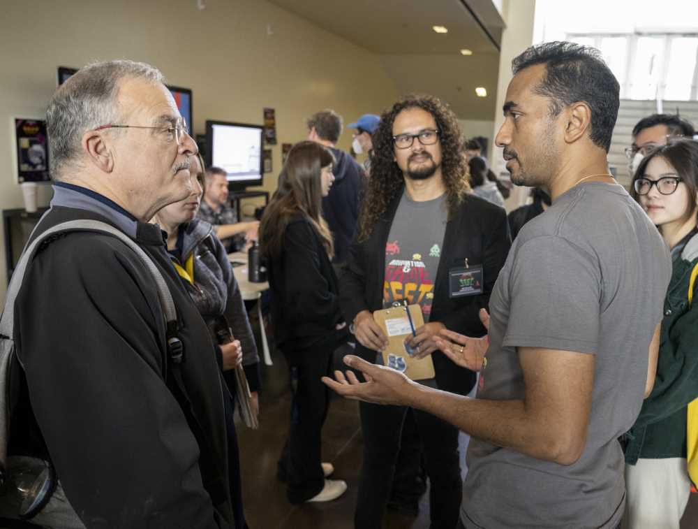 Pofessors Rivas (middle) and Thankamushy (R) talk with attendee to event