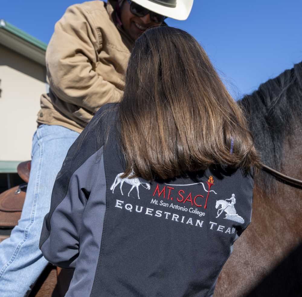 Sara works with staff, wearing a Mt. SAC Equestrian Team jacket