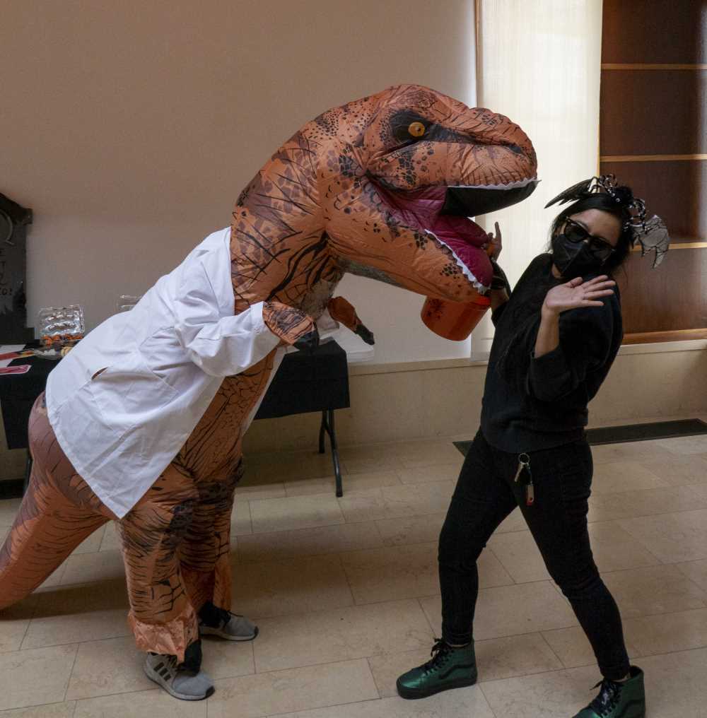 Staff in costume as dinosaur with lab coat terrorizing someone