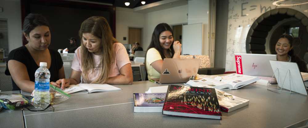 extbooks in foreground with students studying in background