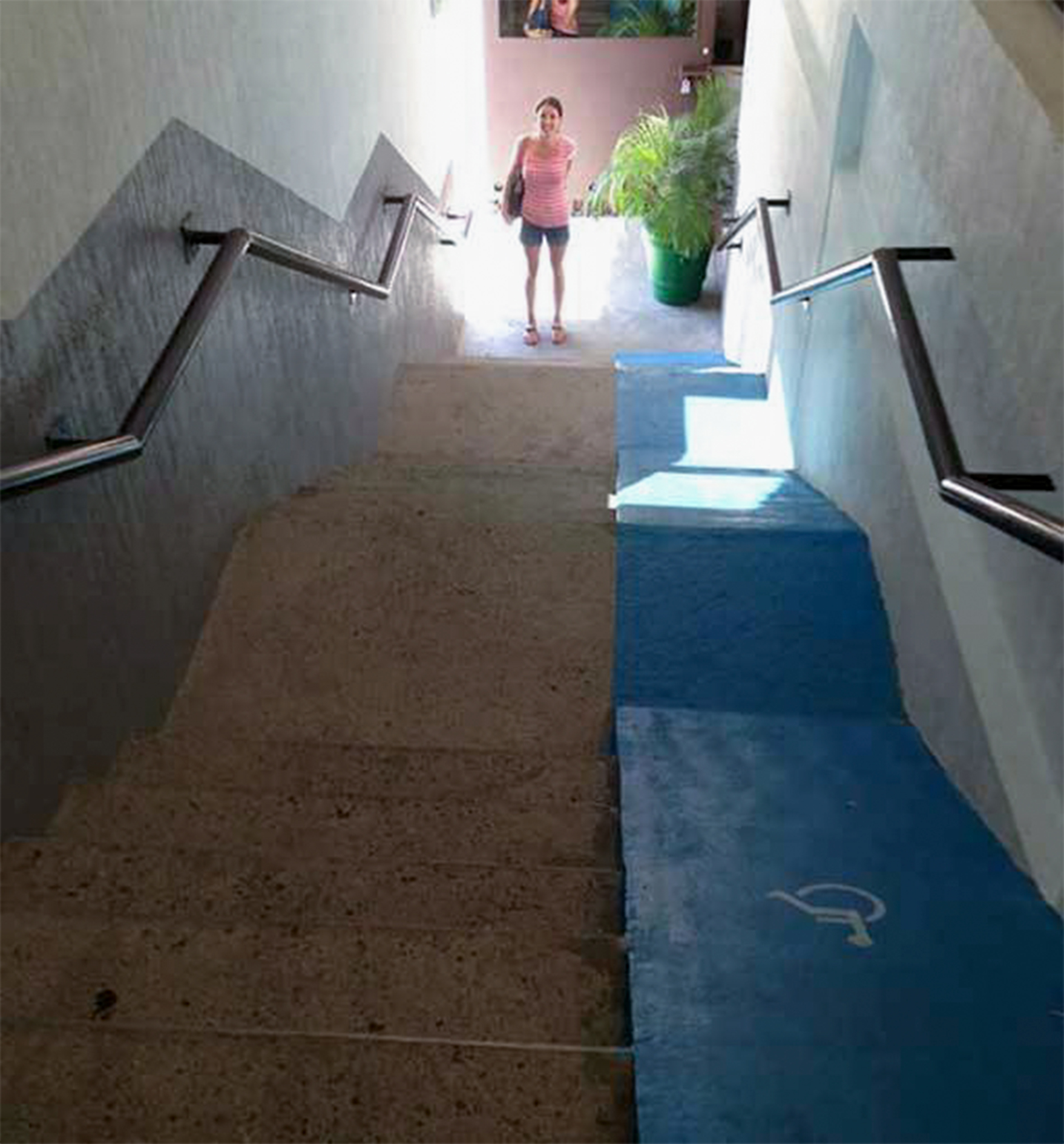 woman standing at bottom of stairs with wheelchair ramp